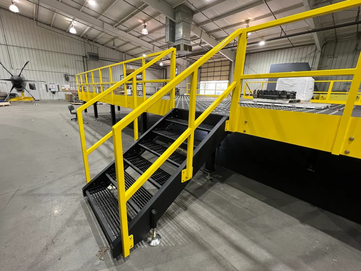 Assembled steel access platform with yellow railings, grated stairs, and bolted connections in Werco's shop